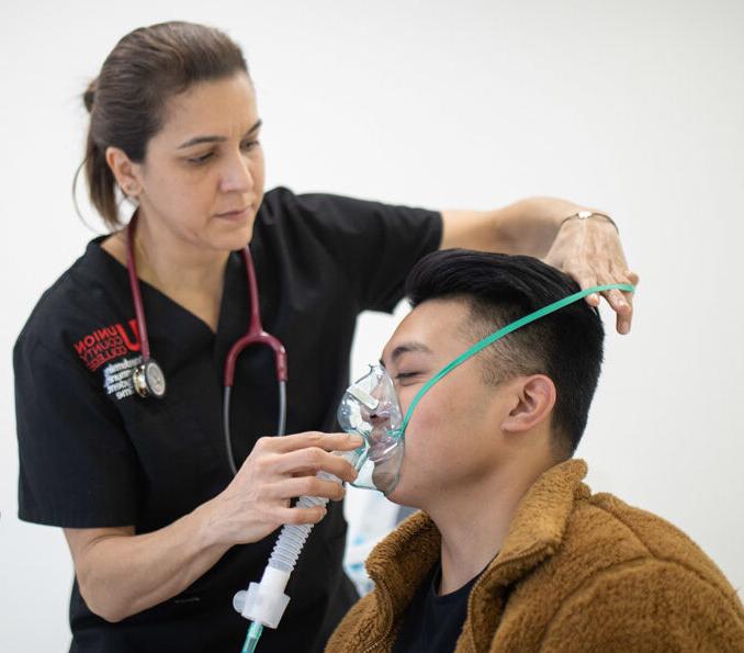 Female nurse putting breathing apparatus over young man's face.